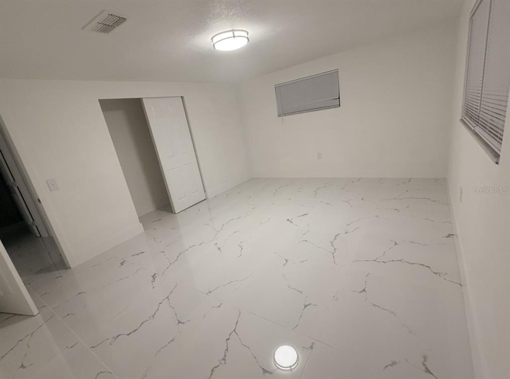 A bedroom with white walls, white marble-patterned tile flooring, and a closet with white doors — 4453 TERRY LOOP, NEW PORT RICHEY, FL