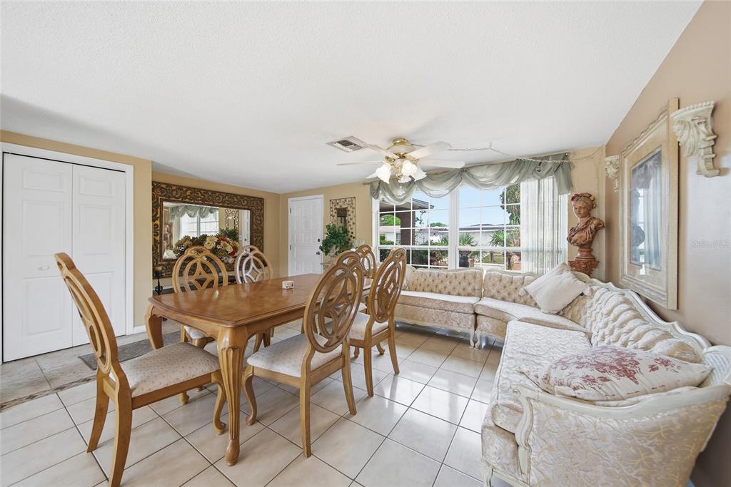 A dining room features a wooden table, chairs, and a sectional sofa on tiled floors — 7140 ROCKWOOD DRIVE, PORT RICHEY, FL