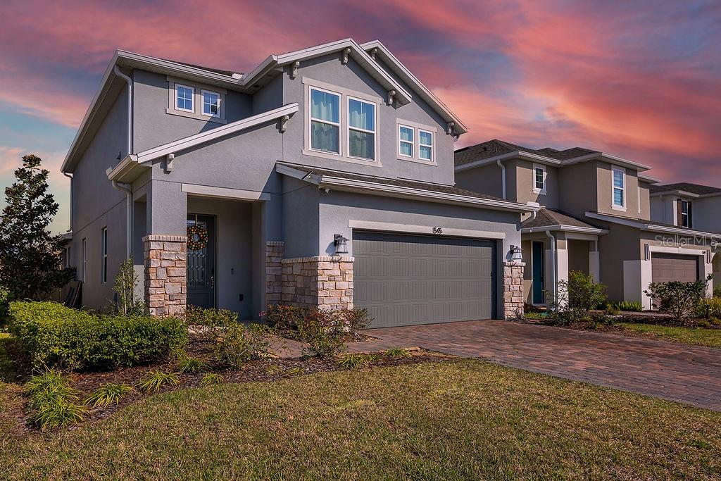 A two-story house with a gray stucco exterior, stone accents, and a paved driveway — 1545 LEAF LANE, KISSIMMEE, FL