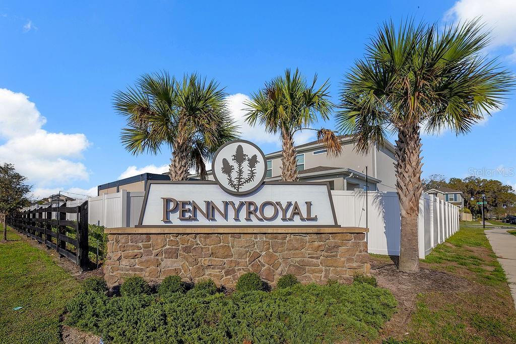 A stone-based monument sign for Pennyroyal stands in front of palm trees and a fence — 1545 LEAF LANE, KISSIMMEE, FL