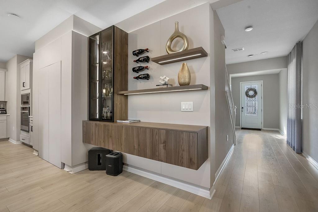A modern home interior featuring a floating wood cabinet, glass display case, and open shelving — 1545 LEAF LANE, KISSIMMEE, FL