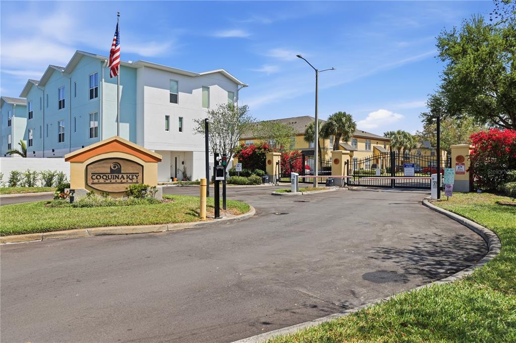 The entrance to Coquina Key Townhomes features a gated driveway, signage, and multi-story residential buildings — 3871 MARINER DRIVE, ST PETERSBURG, FL