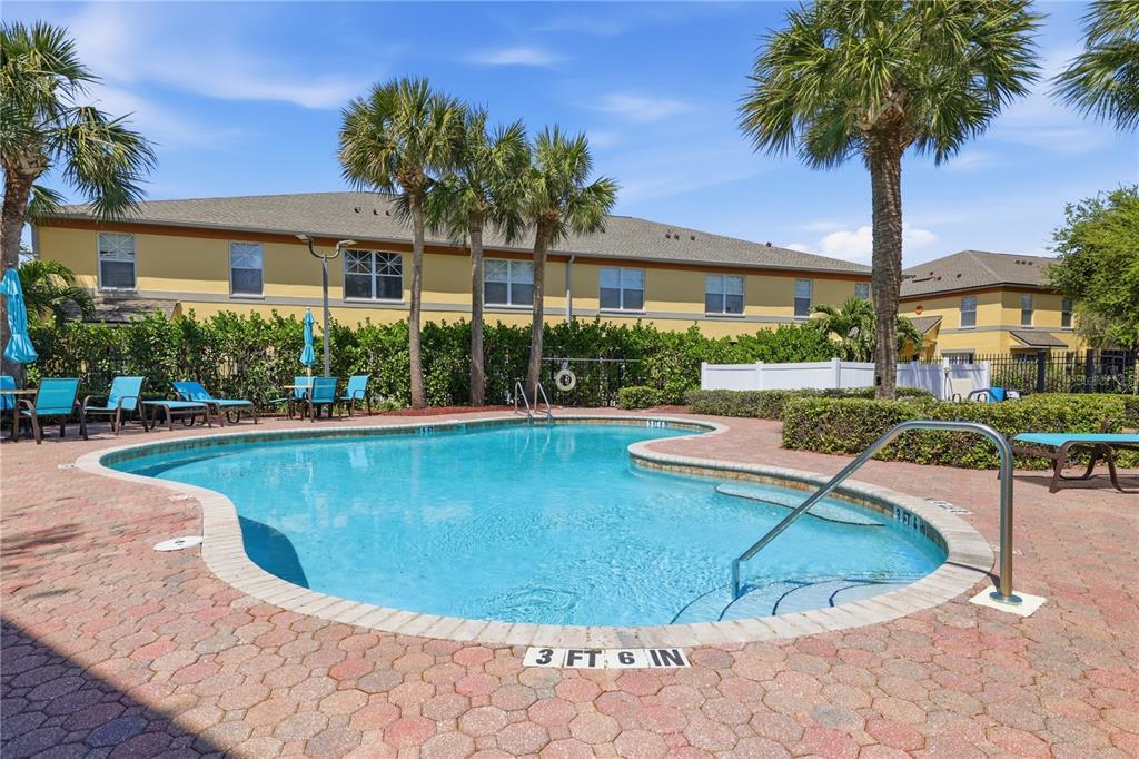 A swimming pool with a brick deck is surrounded by palm trees and apartment buildings — 3871 MARINER DRIVE, ST PETERSBURG, FL