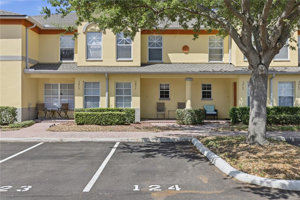 A two-story yellow townhouse exterior features a paved walkway and numbered parking spaces in front — 3871 MARINER DRIVE, ST PETERSBURG, FL