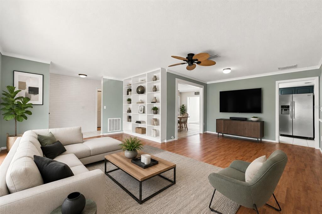A living room features light green walls, wood flooring, a sectional sofa, and built-in shelving — 2069 KINGFISHER DRIVE, PALM HARBOR, FL
