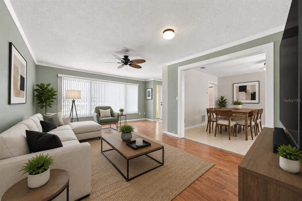A living room with light green walls, wood flooring, and an adjacent dining area — 2069 KINGFISHER DRIVE, PALM HARBOR, FL