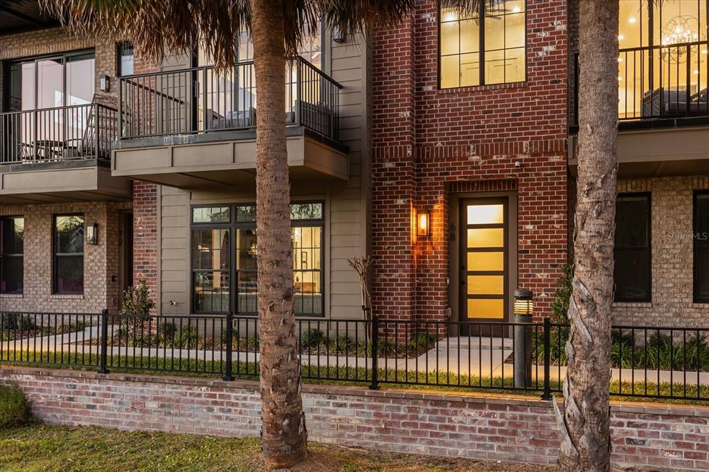 A brick townhouse exterior features a front door, black metal railings, and a second-story balcony — 68 N PARK AVENUE, WINTER GARDEN, FL