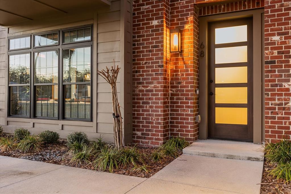A modern brick-front home entrance features a five-panel glass door and a large window — 68 N PARK AVENUE, WINTER GARDEN, FL