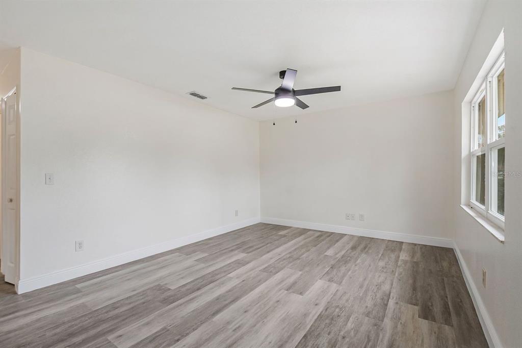 An empty room with white walls, a ceiling fan, and light-colored wood-look flooring — 3220 NETHERWOOD DRIVE, WINTER PARK, FL