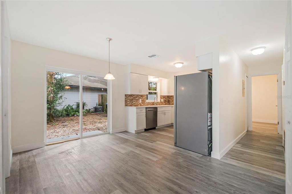 A kitchen and dining area with light wood-look flooring, white cabinets, and a sliding door — 3220 NETHERWOOD DRIVE, WINTER PARK, FL