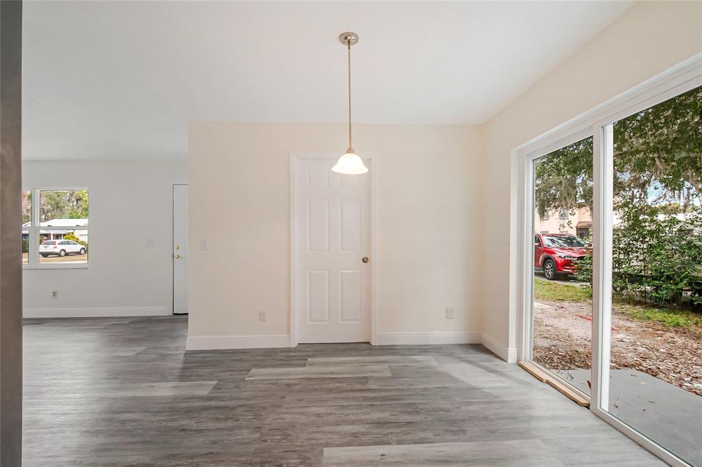 An interior view of a dining area with gray wood-look flooring and a sliding door — 3220 NETHERWOOD DRIVE, WINTER PARK, FL