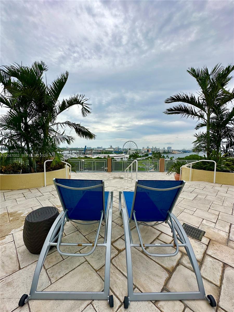Two blue lounge chairs sit on a stone patio overlooking a city skyline and harbor — 244 Biscayne Blvd # 2610, Miami FL 33132, MIAMI, FL
