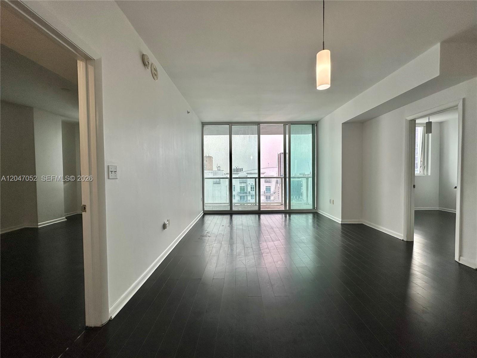 An empty room with dark wood floors, white walls, and floor-to-ceiling windows — 244 Biscayne Blvd # 2610, Miami FL 33132, MIAMI, FL