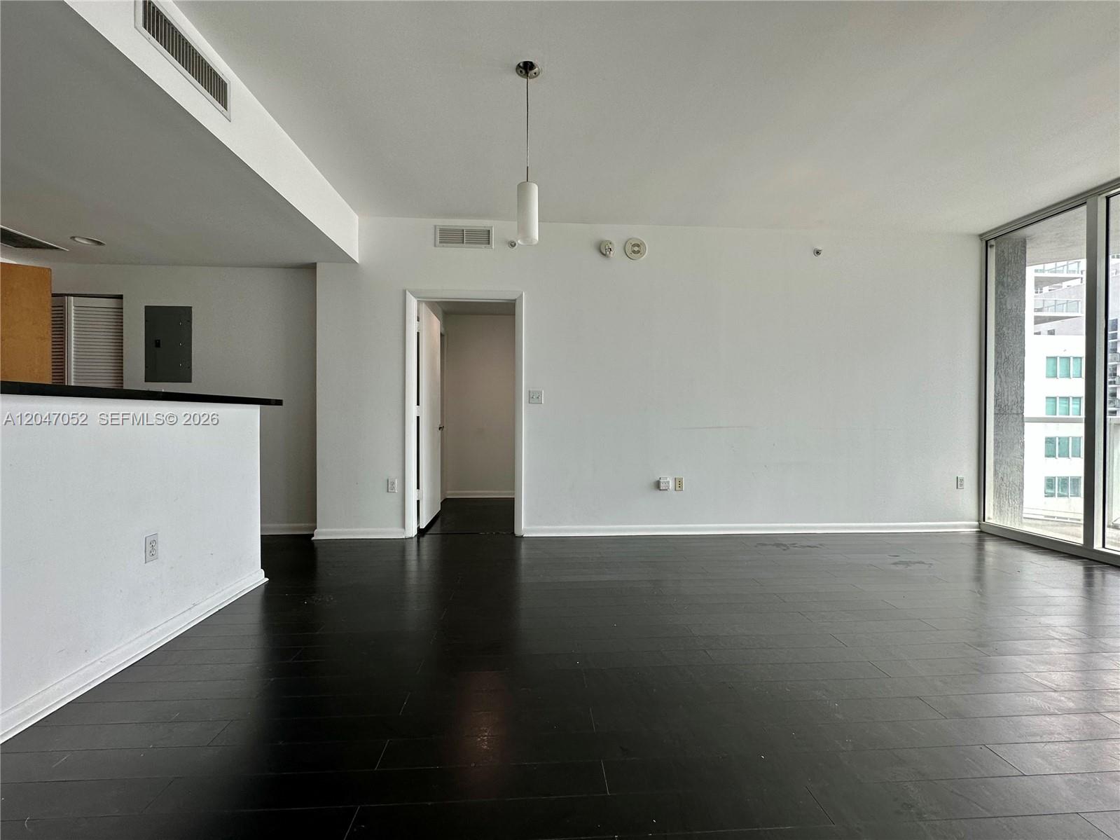 An empty living room features dark wood flooring, white walls, and a sliding glass door — 244 Biscayne Blvd # 2610, Miami FL 33132, MIAMI, FL