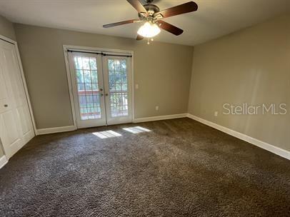 A bedroom with brown carpet, a ceiling fan, and French doors leading to a deck — 12 BUNKER VIEW PLACE, PALM COAST, FL