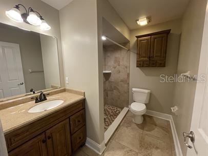 A bathroom features a vanity with a stone countertop, a tiled shower, and a toilet — 12 BUNKER VIEW PLACE, PALM COAST, FL