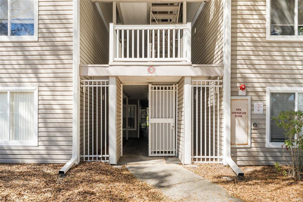An exterior view of an apartment building entrance with a gated walkway and balcony above — 4000 SW 23RD STREET UNIT 2-303, GAINESVILLE, FL