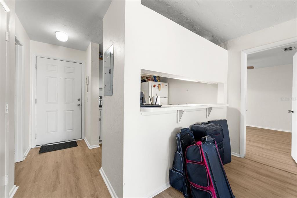 An entryway with light wood flooring, a white front door, and a kitchen pass-through window — 4000 SW 23RD STREET UNIT 2-303, GAINESVILLE, FL