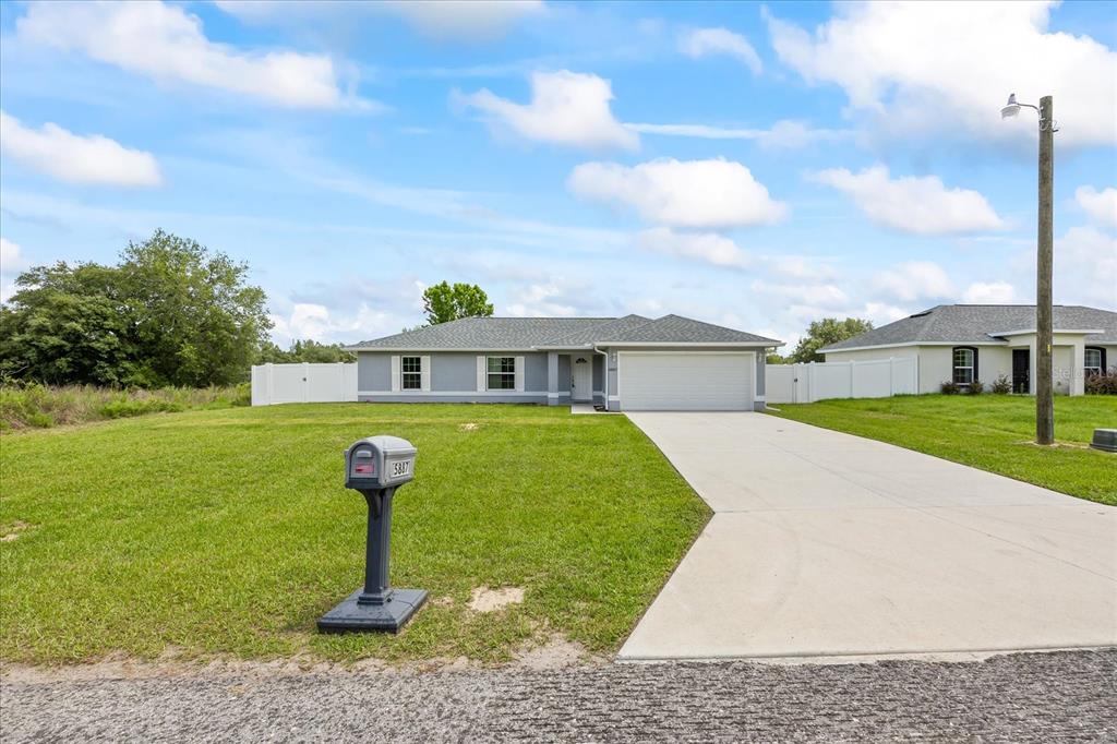 A single-story house with a gray exterior, a two-car garage, and a large front lawn — 5887 SW 154TH LANE ROAD, OCALA, FL