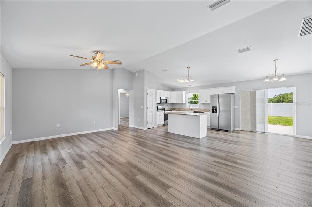 An open-concept living room and kitchen featuring light gray walls and wood-look plank flooring — 5887 SW 154TH LANE ROAD, OCALA, FL