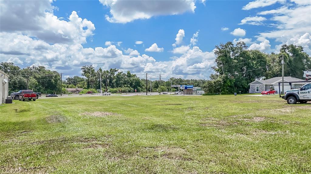A large, grassy vacant lot is shown under a bright, cloudy sky — US 98, DADE CITY, FL