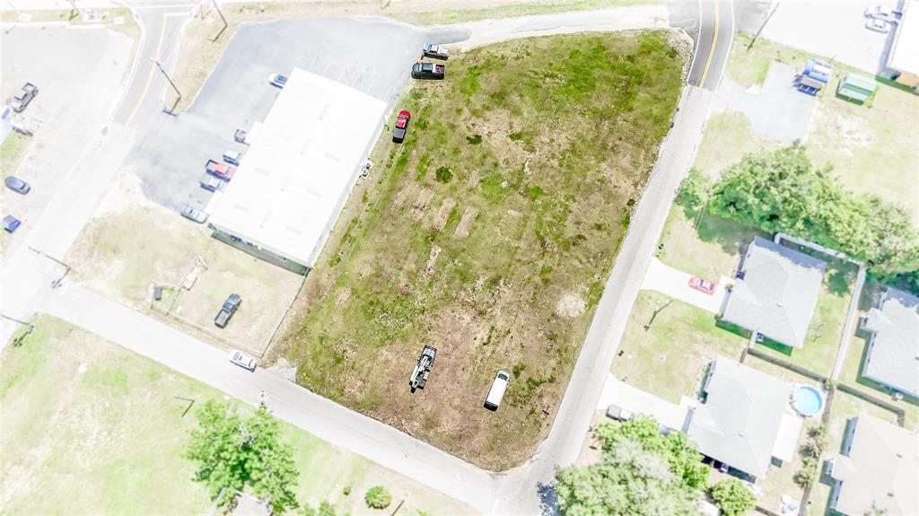 An aerial view shows a vacant, grassy lot situated between a commercial building and houses — US 98, DADE CITY, FL