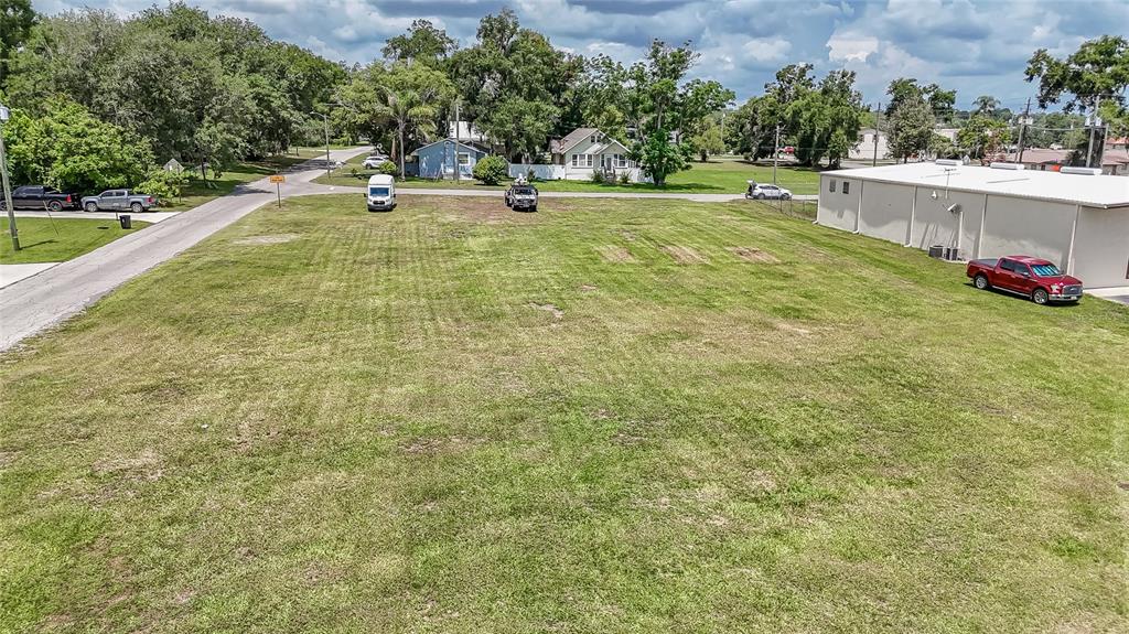An elevated view shows a large, grassy vacant lot next to a commercial building — US 98, DADE CITY, FL