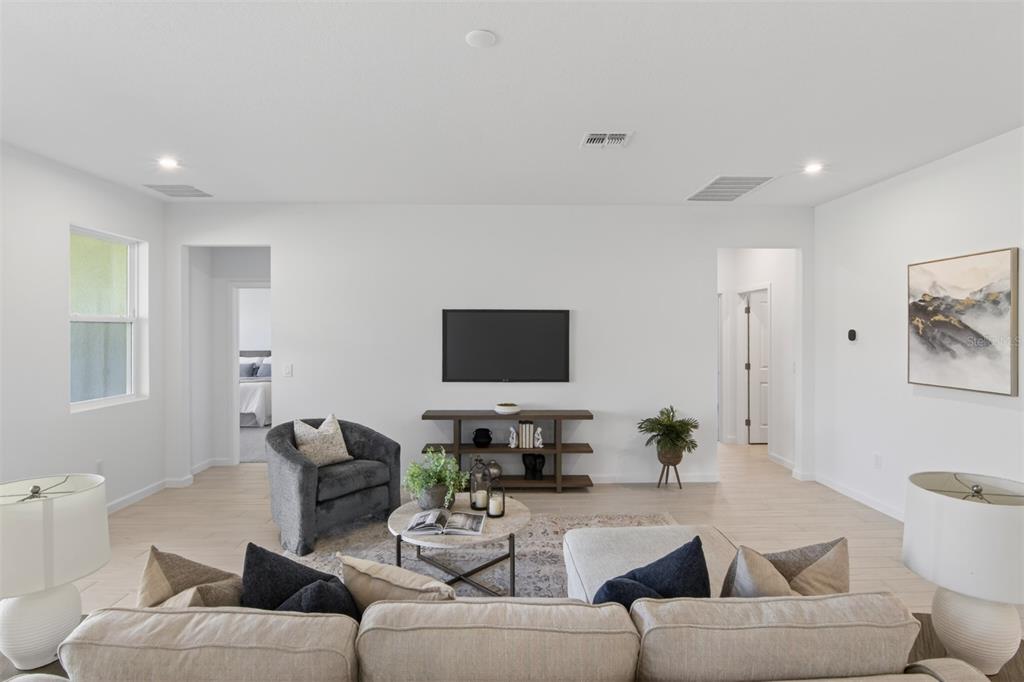 A living room features a beige sectional sofa, a dark armchair, and a wall-mounted television — 2791 SWEET ACACIA DRIVE, CLERMONT, FL