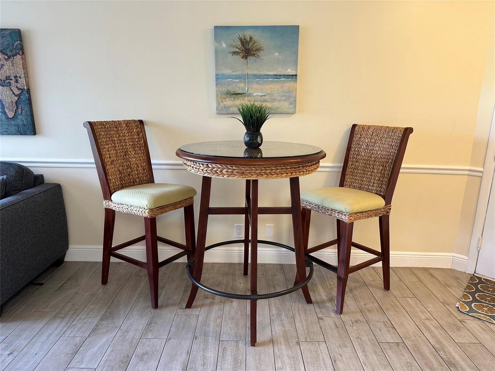 A high-top bistro table with two woven chairs sits against a wall with artwork — 1605 US Highway 1 V-4 # 104, Jupiter FL 33477, JUPITER, FL