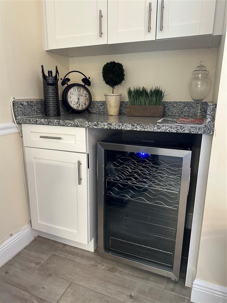 A kitchen wet bar features white cabinets, a granite countertop, and a built-in wine cooler — 1605 US Highway 1 V-4 # 104, Jupiter FL 33477, JUPITER, FL