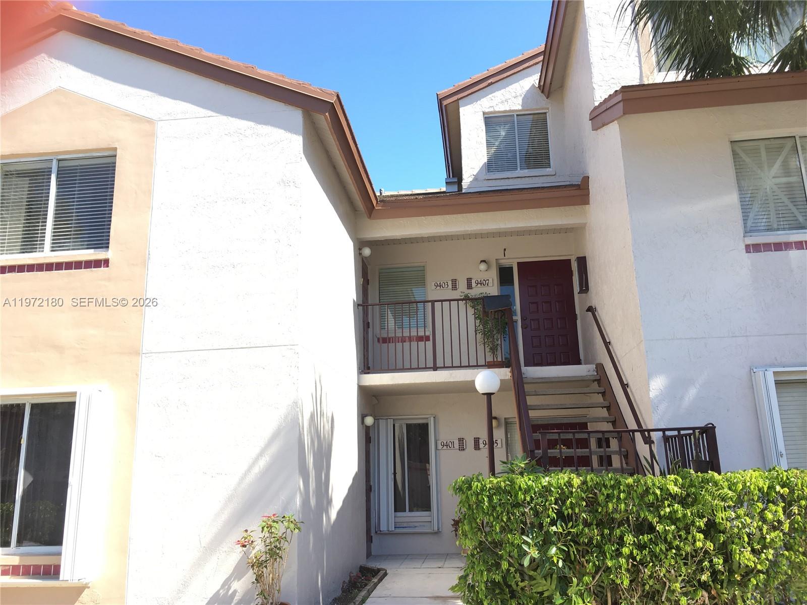 A two-story residential building exterior features white stucco walls, brown trim, and an outdoor staircase — 9403 SW 140th Ct # 9403, Miami FL 33186, MIAMI, FL