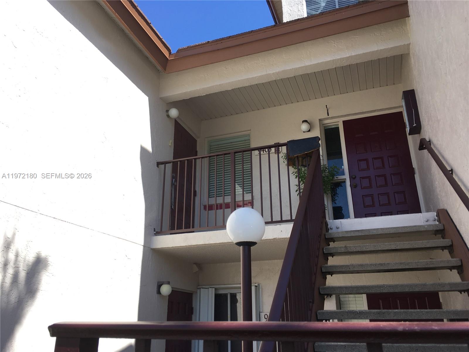 An exterior view shows a two-story building with a staircase leading to an upper balcony — 9403 SW 140th Ct # 9403, Miami FL 33186, MIAMI, FL