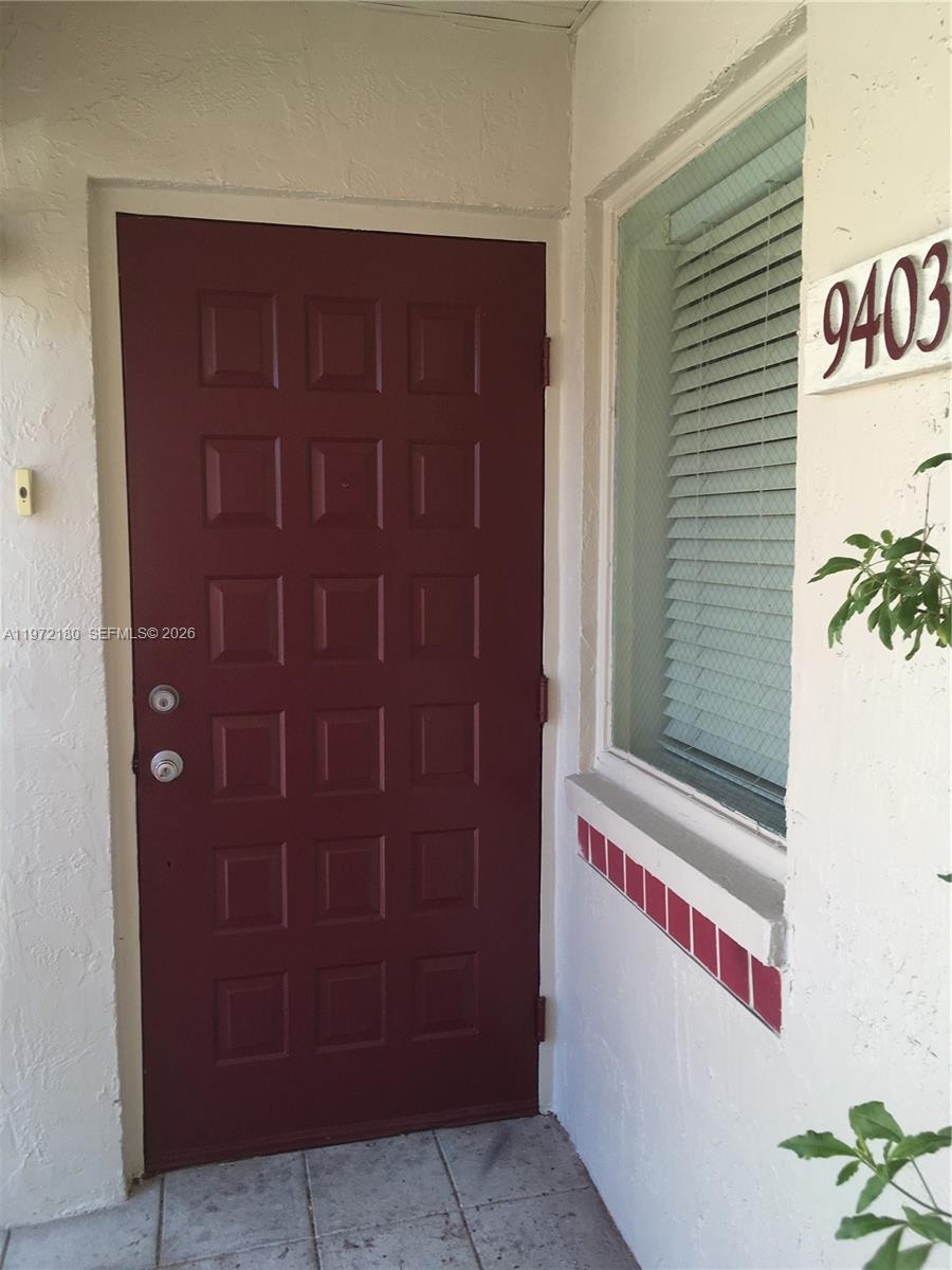 A red paneled front door sits next to a window with blinds and house number 9403 — 9403 SW 140th Ct # 9403, Miami FL 33186, MIAMI, FL