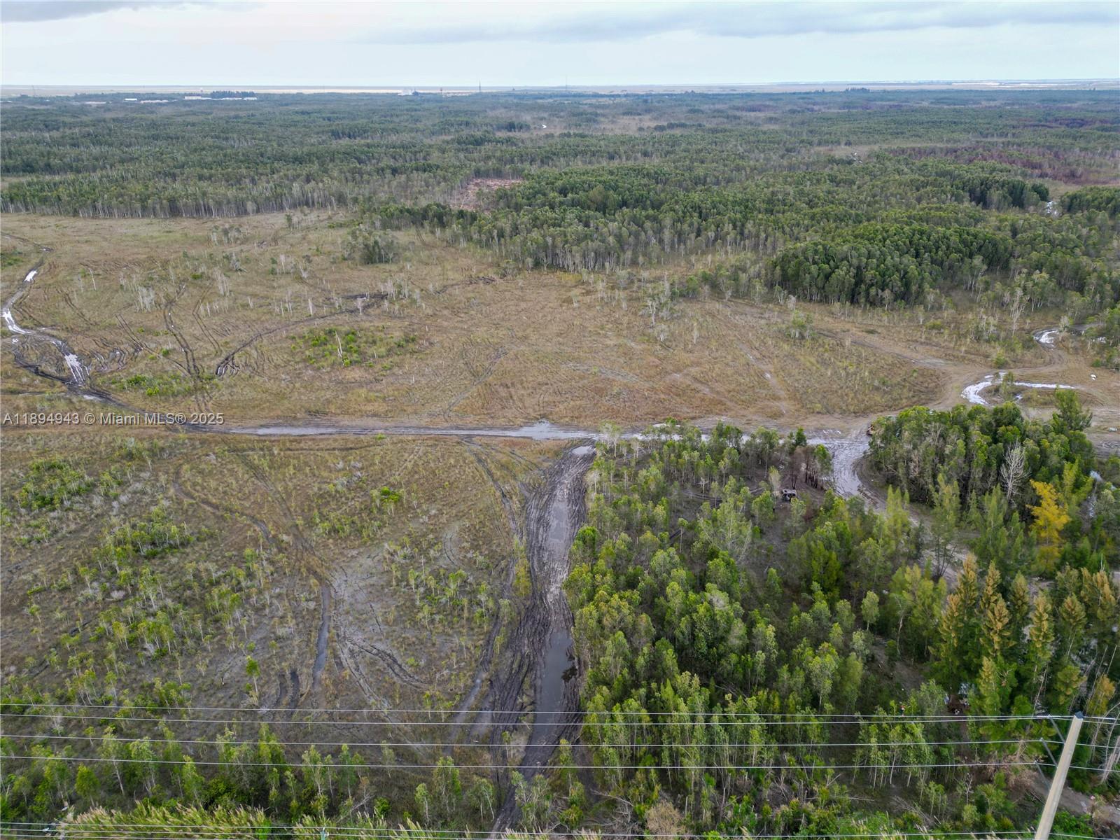 An aerial view shows a muddy, undeveloped landscape with patches of trees and tire tracks — 172 Ave SW 38-39 St, Miami FL 33185, MIAMI, FL