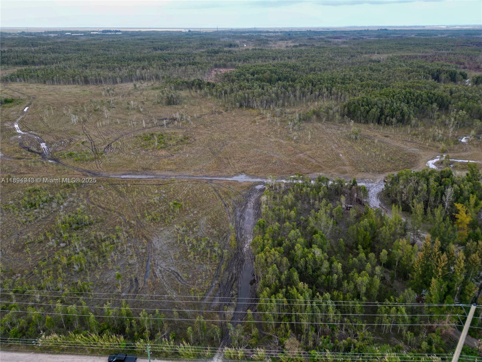 An aerial view shows a muddy, undeveloped lot with sparse trees and tire tracks — 172 Ave SW 38-39 St, Miami FL 33185, MIAMI, FL