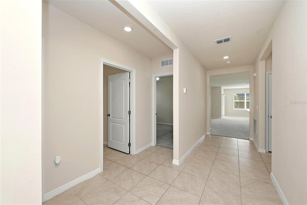 A tiled hallway leads to an open living area with carpeted floors and white doors — 2725 DUMONT LANE, TAVARES, FL