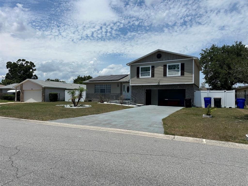 A two-story house with a gray driveway, a garage, and solar panels on the roof — 4612 MESA VERDE DRIVE, ST CLOUD, FL