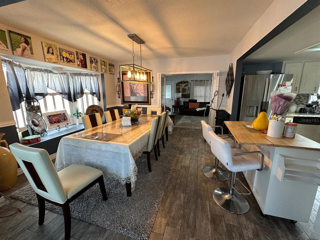 A dining room with a long table, white chairs, and a kitchen island with stools — 4612 MESA VERDE DRIVE, ST CLOUD, FL