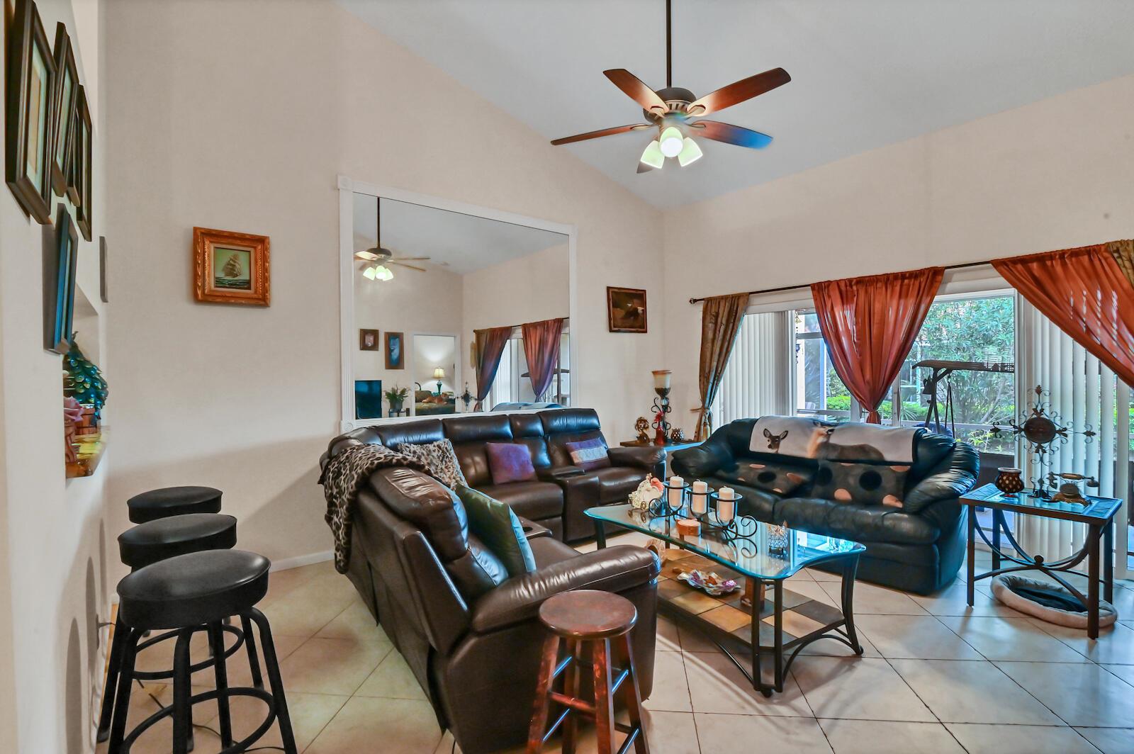 A living room features leather sofas, a glass coffee table, tile flooring, and a large mirror — 8072 Key West Lane, Boynton Beach FL 33472, BOYNTON BEACH, FL