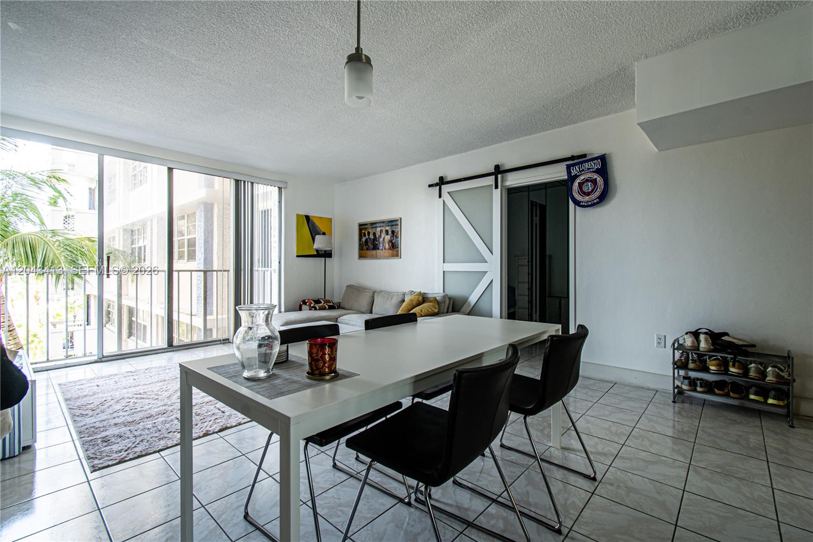 A dining area with a white table and black chairs sits before a living room — 800 West Ave # 414, Miami Beach FL 33139, MIAMI BEACH, FL