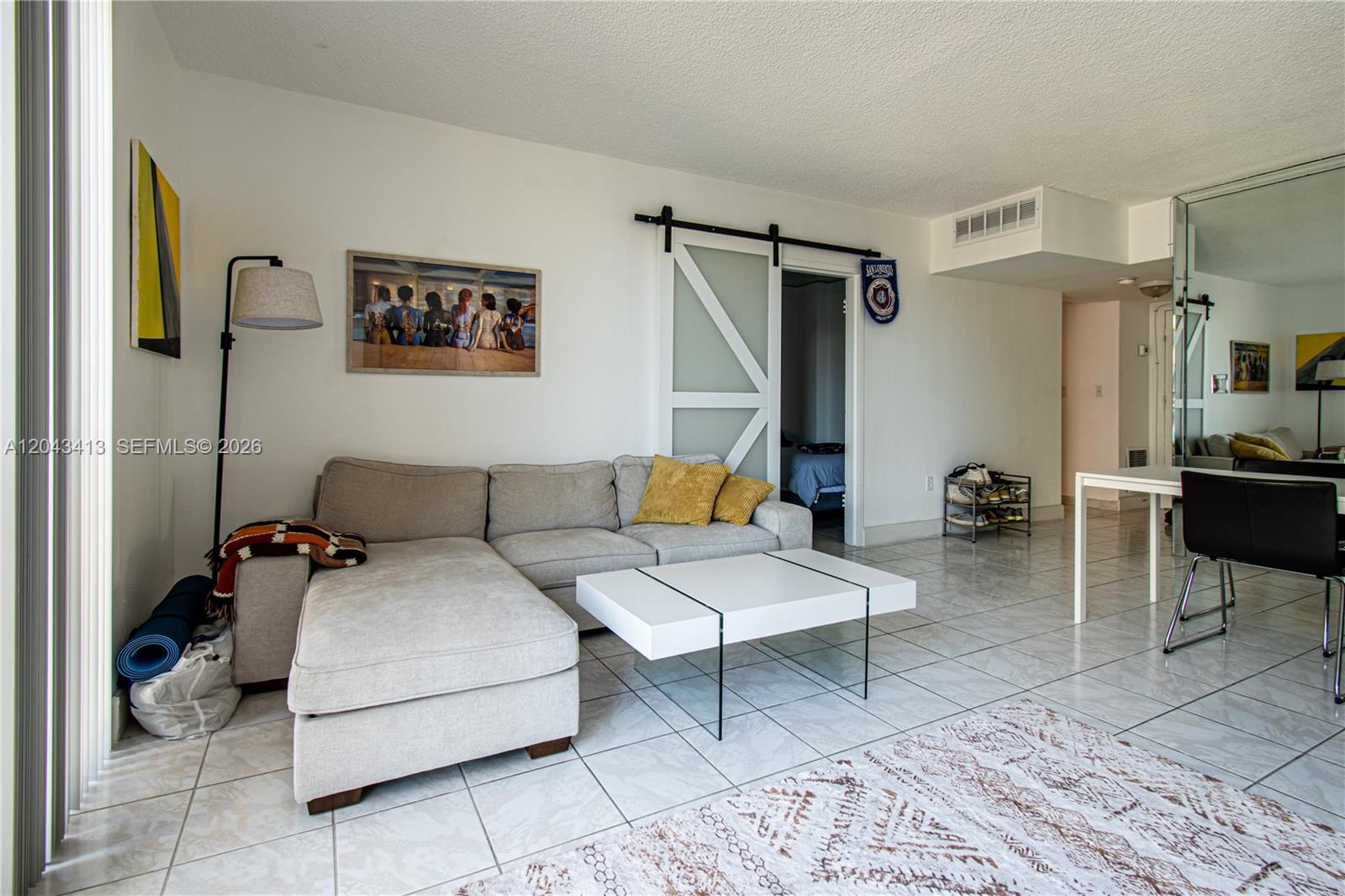A living room features a sectional sofa, a white coffee table, and a sliding barn door — 800 West Ave # 414, Miami Beach FL 33139, MIAMI BEACH, FL