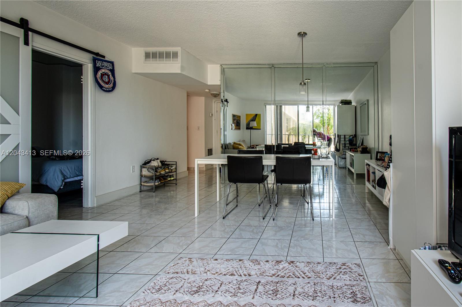 A dining area with a white table and black chairs sits before a mirrored wall — 800 West Ave # 414, Miami Beach FL 33139, MIAMI BEACH, FL