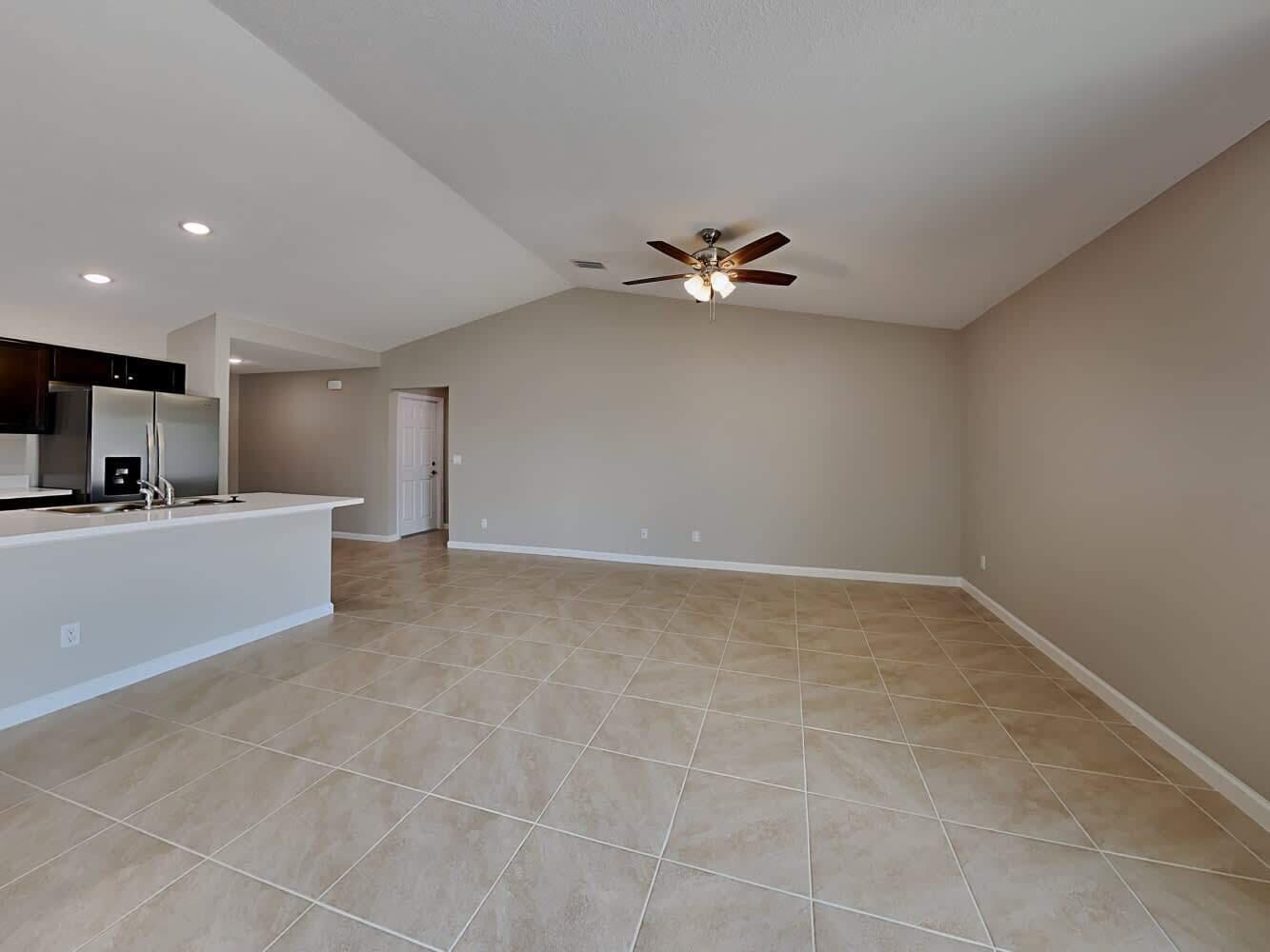 An open-concept living area features vaulted ceilings, tile flooring, and an adjacent kitchen — PORT ST. LUCIE, FL