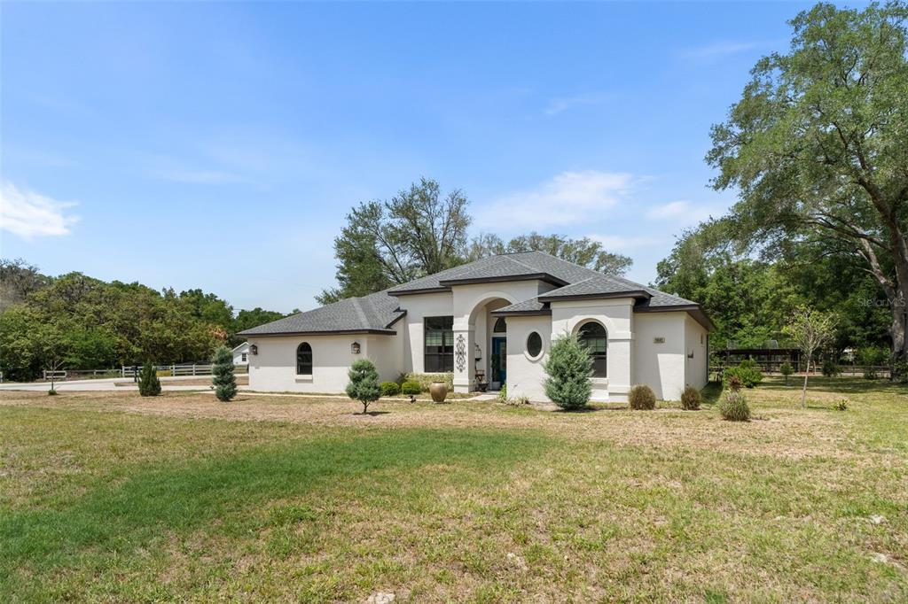 A single-story white stucco house with a dark roof sits on a grassy lot — 11645 SW 134TH COURT, DUNNELLON, FL