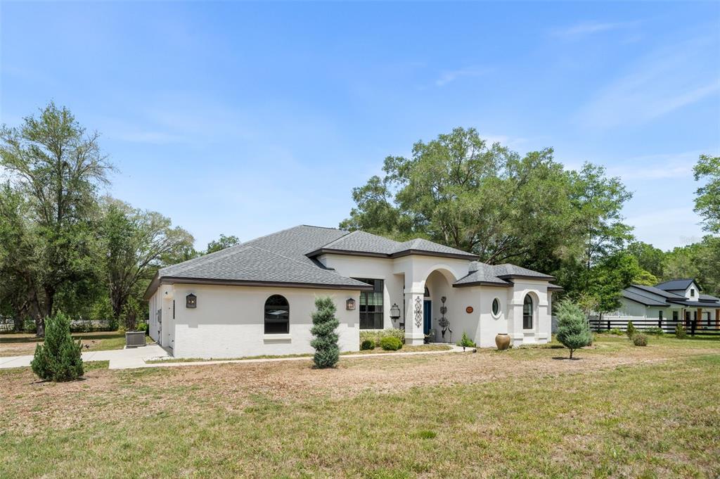 A single-story stucco house with a gray shingled roof sits on a grassy lot — 11645 SW 134TH COURT, DUNNELLON, FL