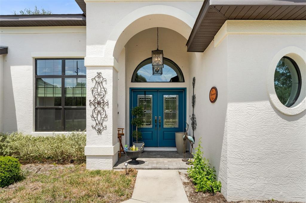 The exterior of a house features a blue double front door under an arched entryway — 11645 SW 134TH COURT, DUNNELLON, FL