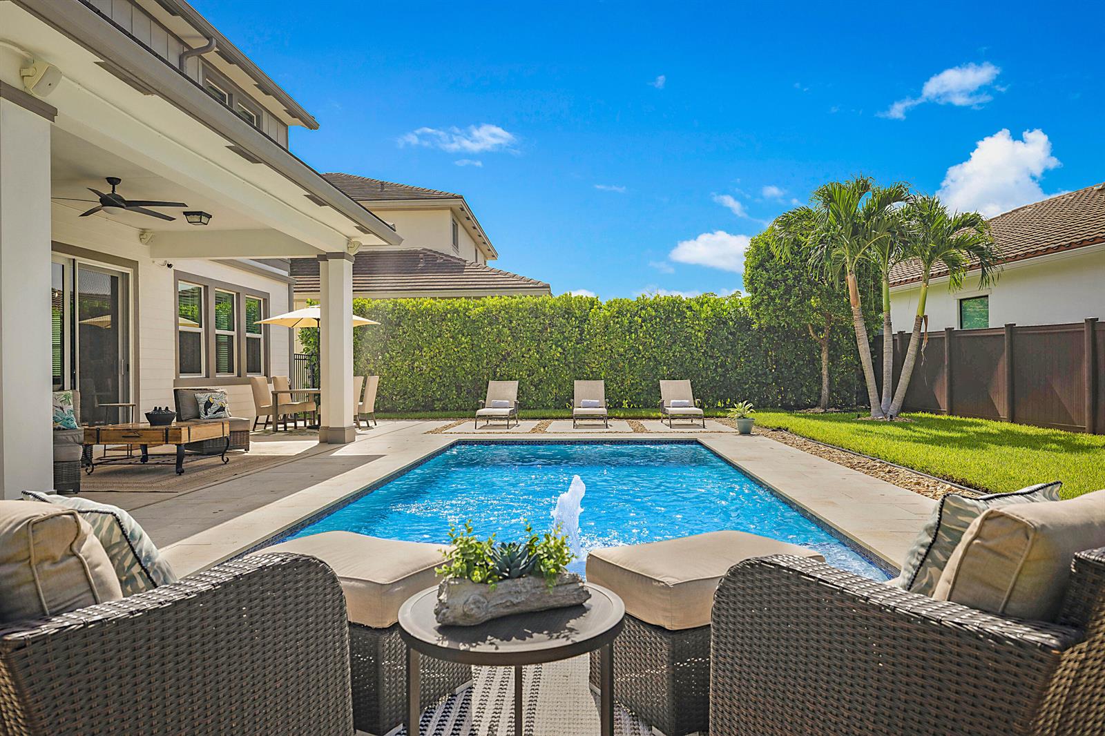 A backyard features a rectangular swimming pool with a fountain, lounge chairs, and patio furniture — 19671 Split Rail Run, Loxahatchee FL 33470, LOXAHATCHEE, FL