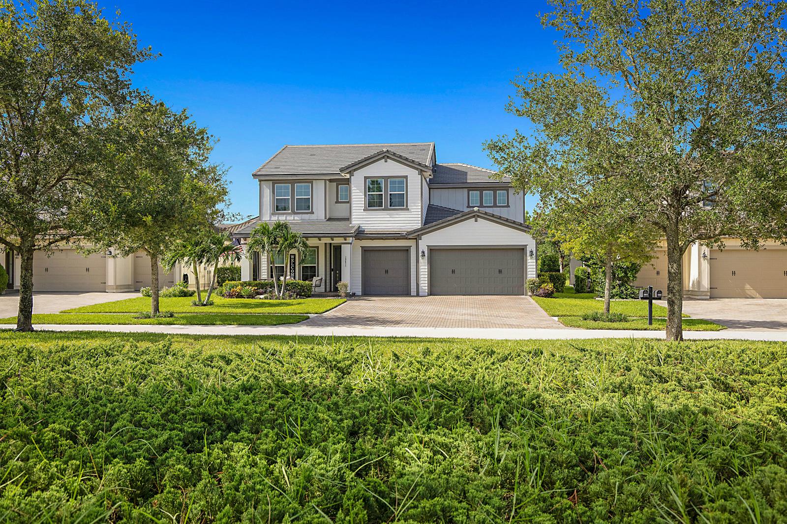 A two-story suburban house with a gray tile roof, white siding, and a three-car garage — 19671 Split Rail Run, Loxahatchee FL 33470, LOXAHATCHEE, FL