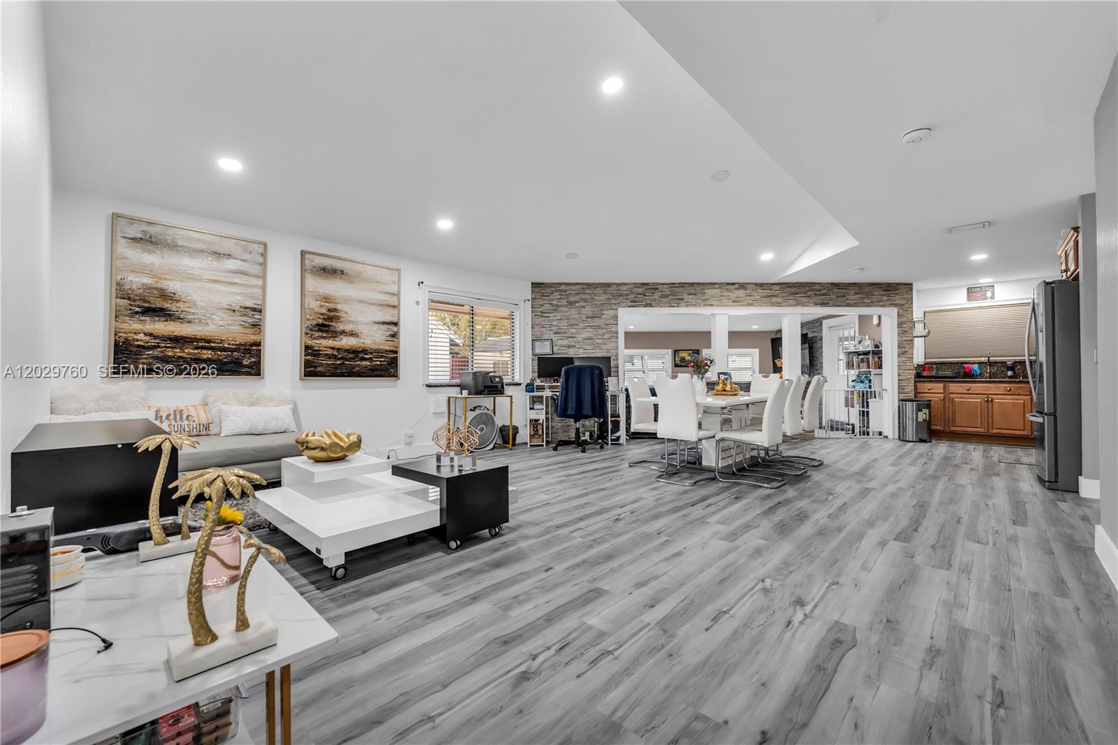 An open-concept living and dining area features gray wood-look flooring and a stone accent wall — 1721 SW 87th Ter, Miramar FL 33025, MIRAMAR, FL