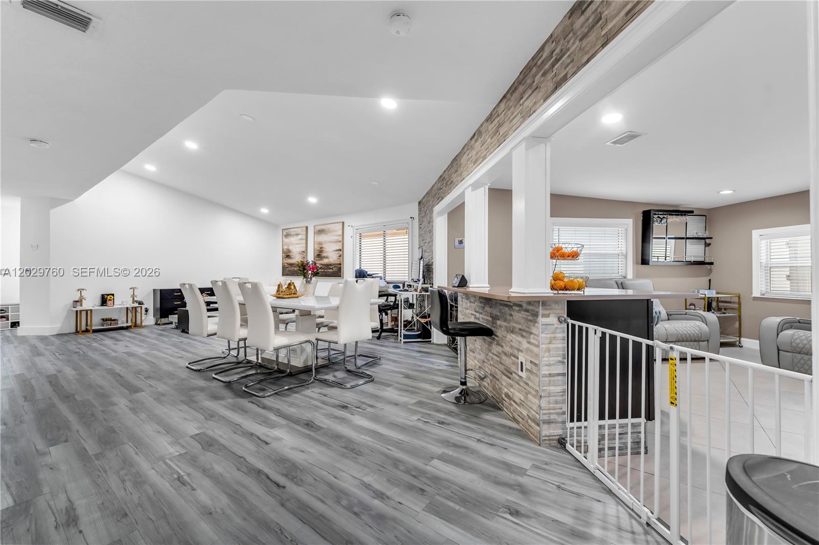 An open-concept dining area features gray wood-look flooring, white chairs, and a stone-accented breakfast bar — 1721 SW 87th Ter, Miramar FL 33025, MIRAMAR, FL
